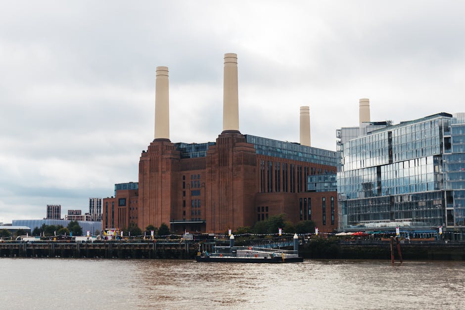An upward view of Battersea Power Station's brick façade, featuring multiple rectangular windows with black frames, some with reflective glass panes, and two tall, cylindrical chimneys extending into