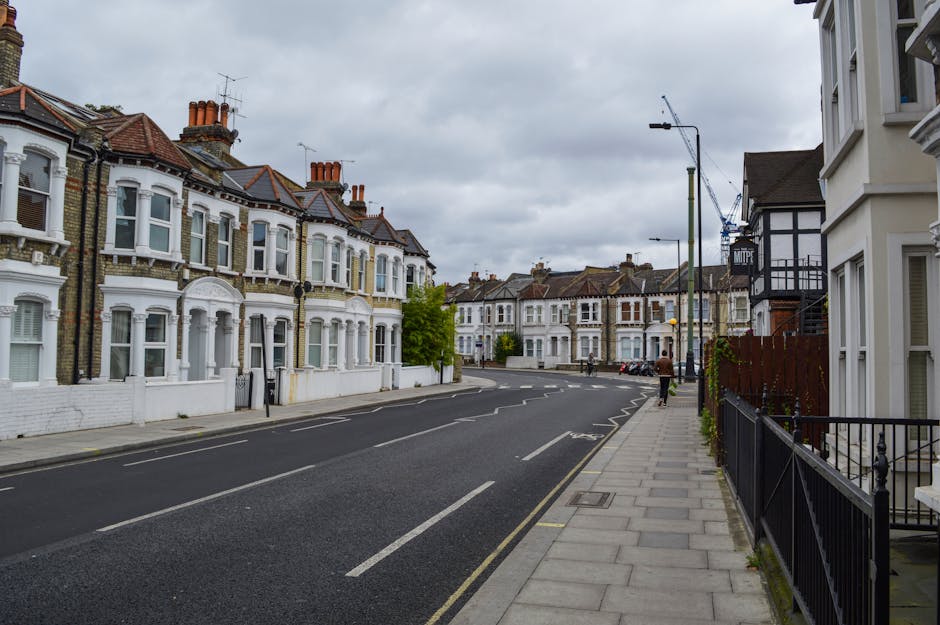 Inside a property, a team from Battersea Man and Van is engaged in a home relocation process. Several cardboard boxes, some wrapped in plastic and others open, are arranged on the floor and near a doo